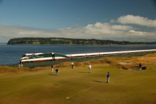 The 16th hole is set up for Wednesday's practice round as a train speeds by along Puget Sound (cortesía USGA)